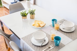 Ett frukostbord med en tallrik rostat bröd, en skål, en kopp och ett glas apelsinjuice.