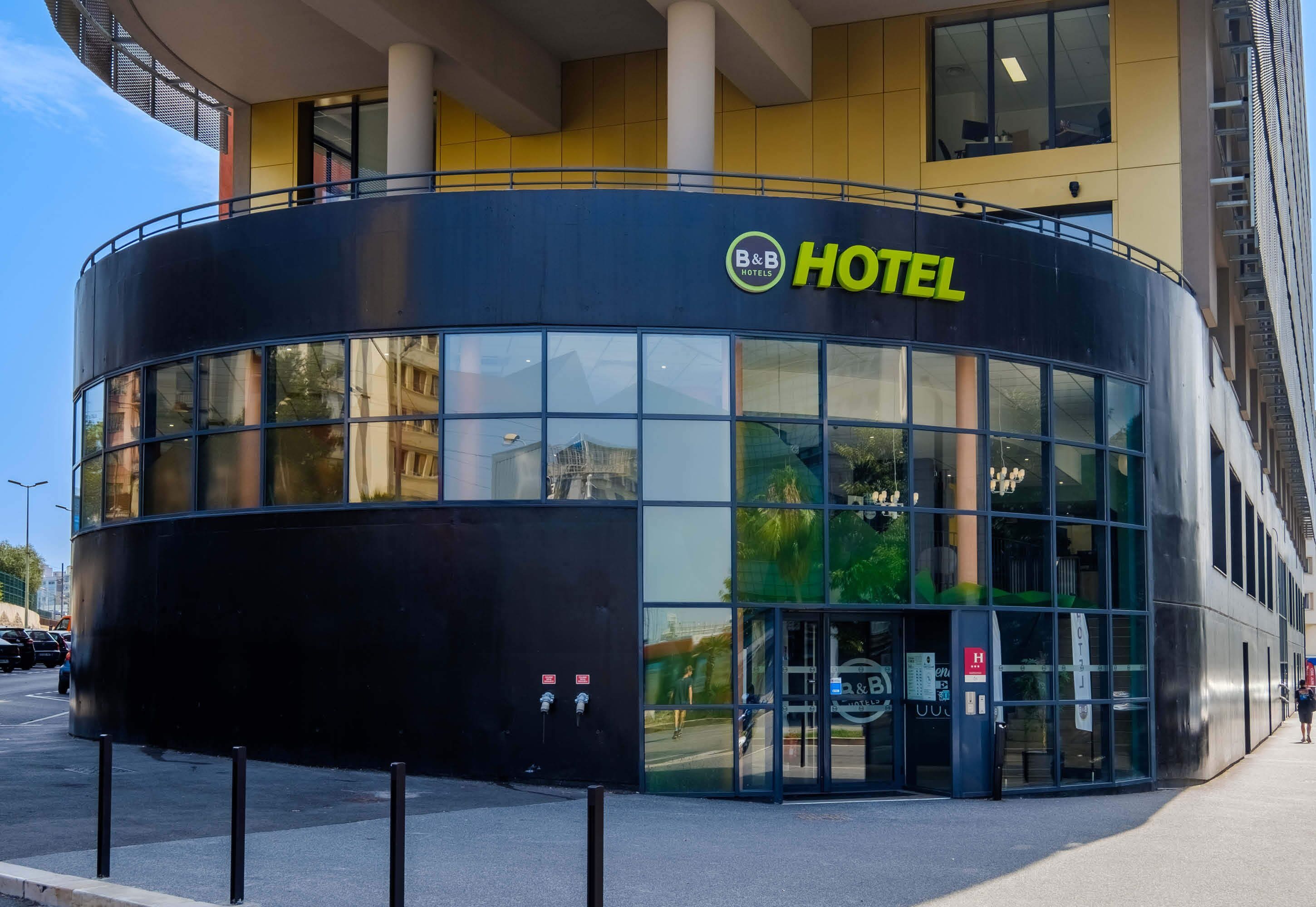 A modern hotel with a curved facade, large glass windows, and a prominent B&B Hotels logo.