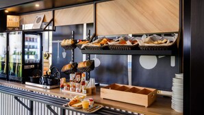 Una barra de desayuno con cestas de pasteles, un refrigerador y provisiones para el desayuno.