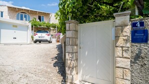 A residential building with a stone gate, a garage, and a car parked in front. - Guest House Vulic (Dubrovnik)