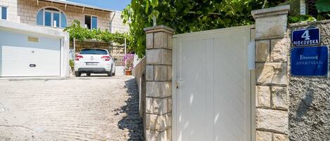 A residential building with a stone gate, a garage, and a car parked in front.