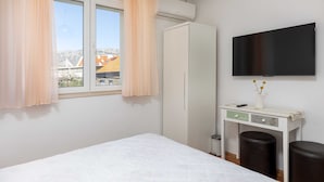 A bedroom with a bed, a wardrobe, a desk with a chair, and a TV on the wall. - Guest House Vulic (Dubrovnik)