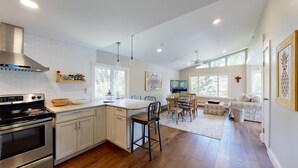 A modern kitchen with a large island, a dining area with a table and chairs, and a cozy seating area with a sofa. - River House on the River (Gunnison)