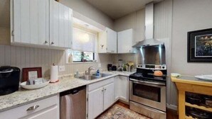 A modern kitchen with white cabinets, stainless steel appliances, and a wooden countertop. - Aspen House by the River (Gunnison)