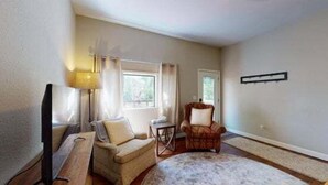 A living room with a sofa, armchair, TV, and a lamp. - Aspen House by the River (Gunnison)
