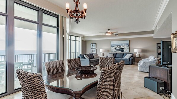 A spacious living room with a large dining table, comfortable seating, and a view of the ocean. - Phoenix West beachfront 3BR/4BA with Lazy River/Slide (Orange Beach)