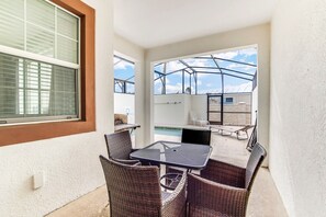 Enjoy a refreshing view of the pool from this balcony with a table and four chairs.