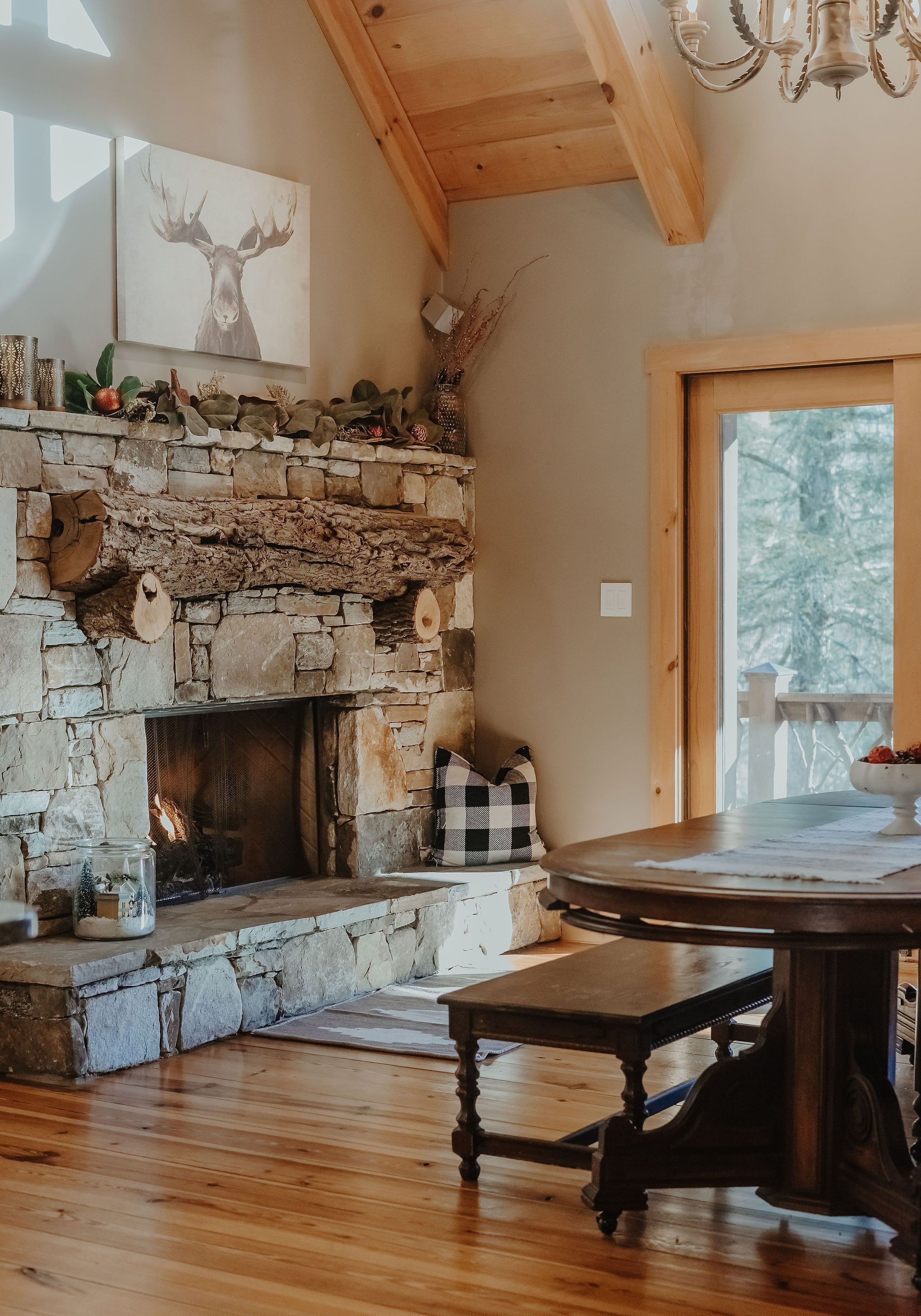 A rustic stone fireplace with a checkered pillow and a table in front.