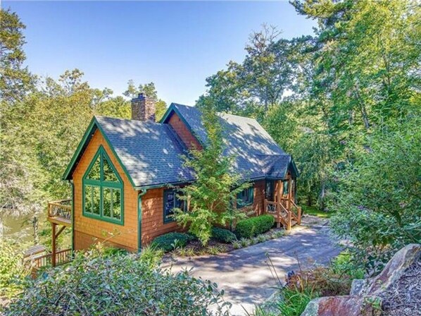 Une cabane avec une façade en bois, une cheminée et une véranda.