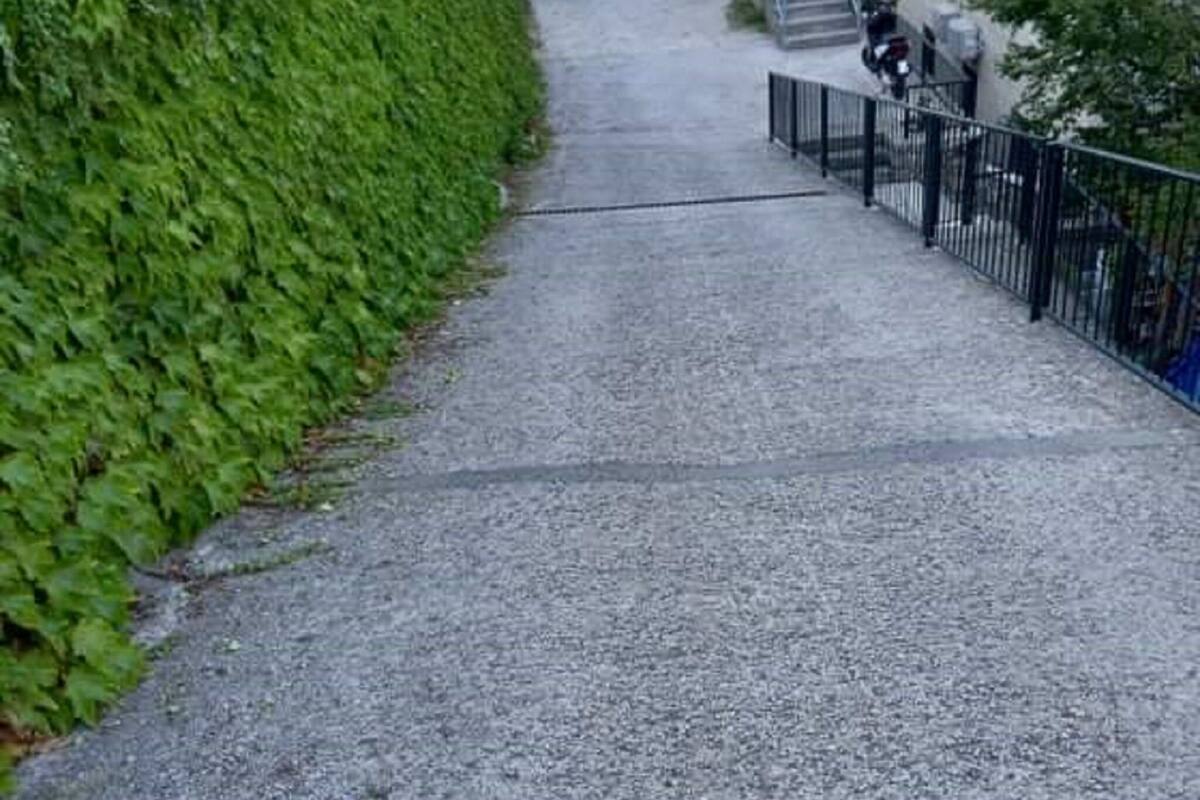 A narrow, gravel pathway leading to a building with a staircase.