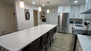 A modern kitchen with a large island, stainless steel appliances, and pendant lighting.