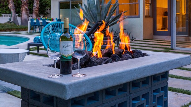 A modern outdoor seating area with a fire feature, a bottle of wine, and glasses. - Marcia! Marcia! Marcia! – Mid-Mod PS Retreat (Palm Springs)