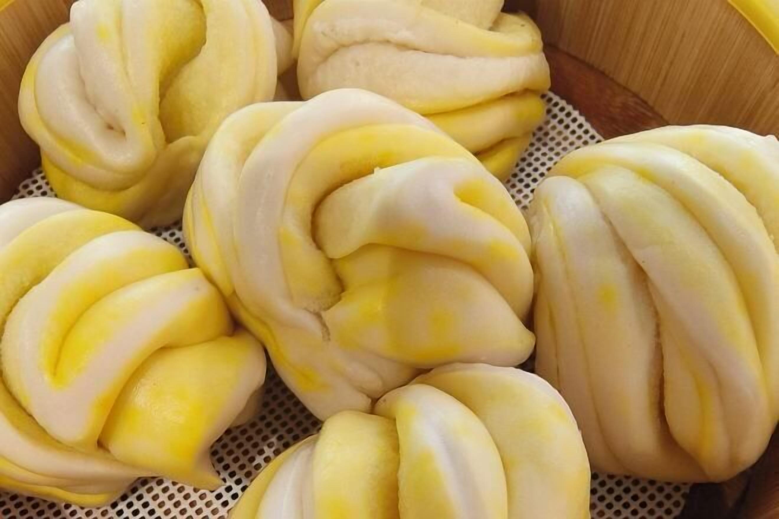 Una confezione di baozi gialli e bianchi al vapore.