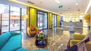 Eine moderne Lobby mit einer Rezeption, einer Sitzecke und großen Fenstern mit Blick auf die Straße.
