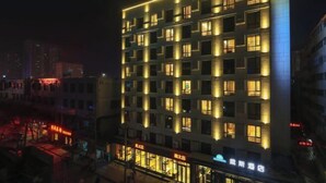 Ein mehrstöckiges Hotel mit beleuchteten Fenstern und einem Restaurant im Erdgeschoss.