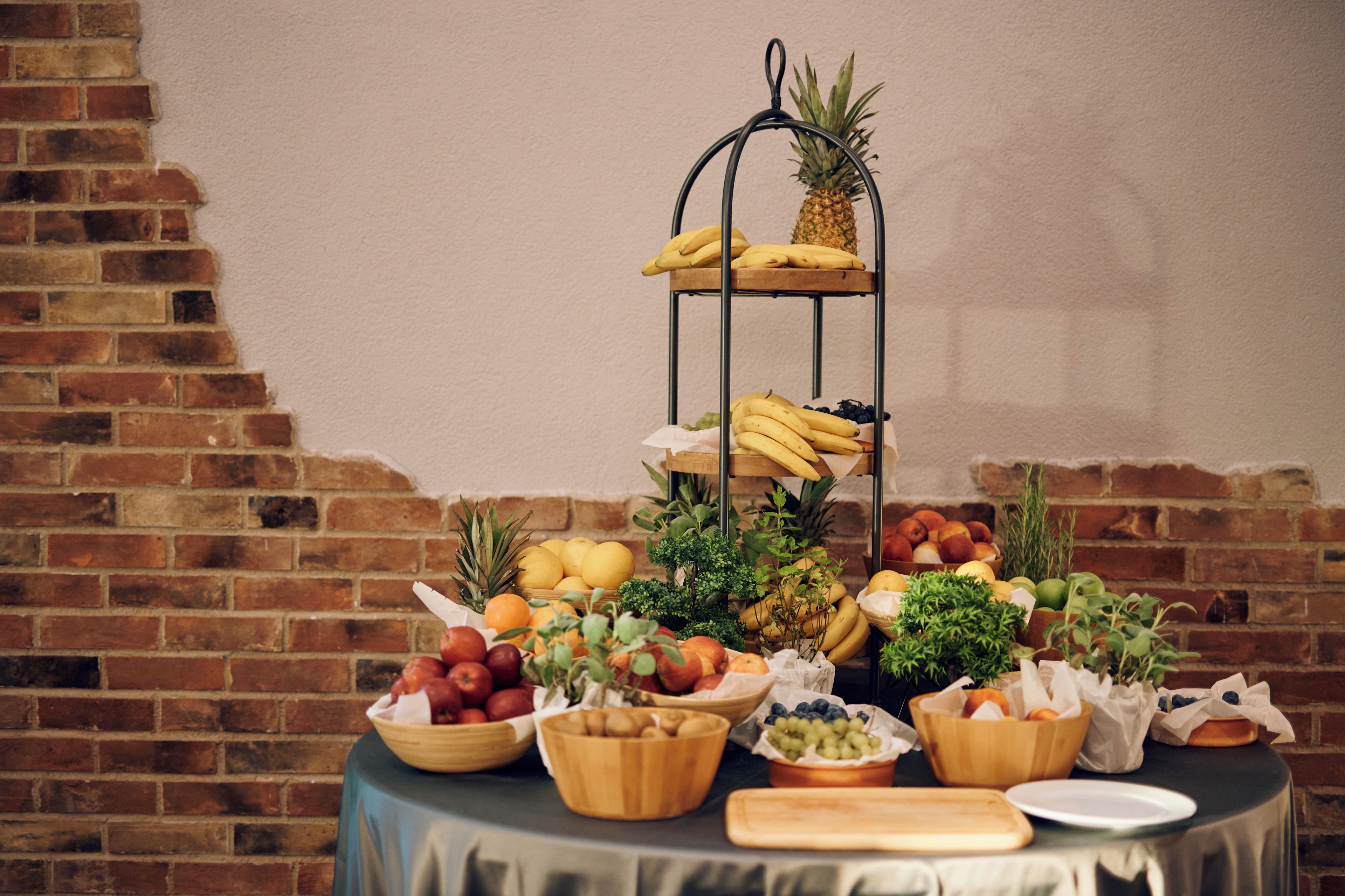 Fruit en groenten op een tafel, met een bakstenen muur op de achtergrond.
