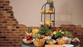 Fruit en groenten op een tafel, met een bakstenen muur op de achtergrond.