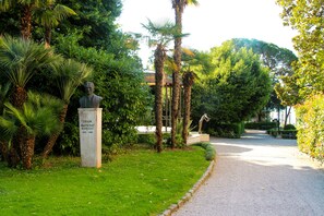 A statue in a garden with a pathway leading to a building. - Paris (Opatija)