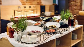 Uma mesa de buffet com diversos pratos, um espaço para café e um fundo com parede de tijolos.