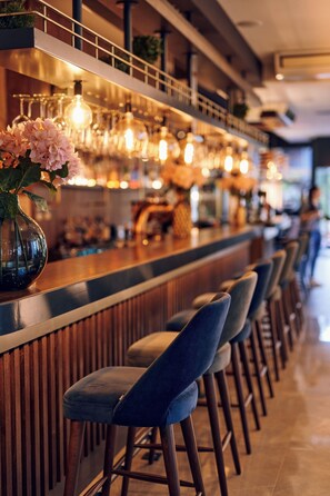 A bar area with a long counter, multiple stools, and hanging light fixtures. - Paris (Opatija)