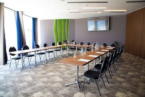 A conference room with long tables and chairs, a flat-screen TV on the wall, and a green vertical garden. - Paris (Opatija)