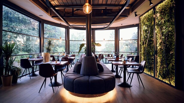 A modern restaurant with a central seating area, large windows, and a green wall. - Paris (Opatija)