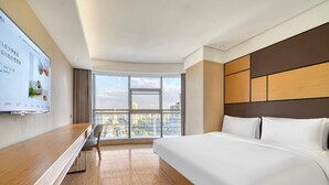 Une chambre d’hôtel avec un grand lit, un bureau et un téléviseur fixé au mur.