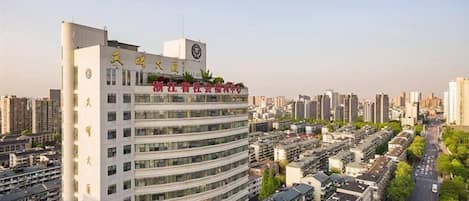 A multi-story hotel with a curved facade, multiple balconies, and a clear view of the surrounding urban area.