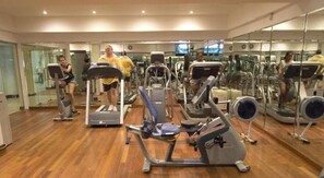 Un gimnasio con cintas de correr, elípticas y bicicletas estáticas.