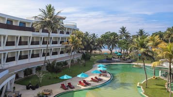Un hotel con piscina, sillas de descanso y palmeras.