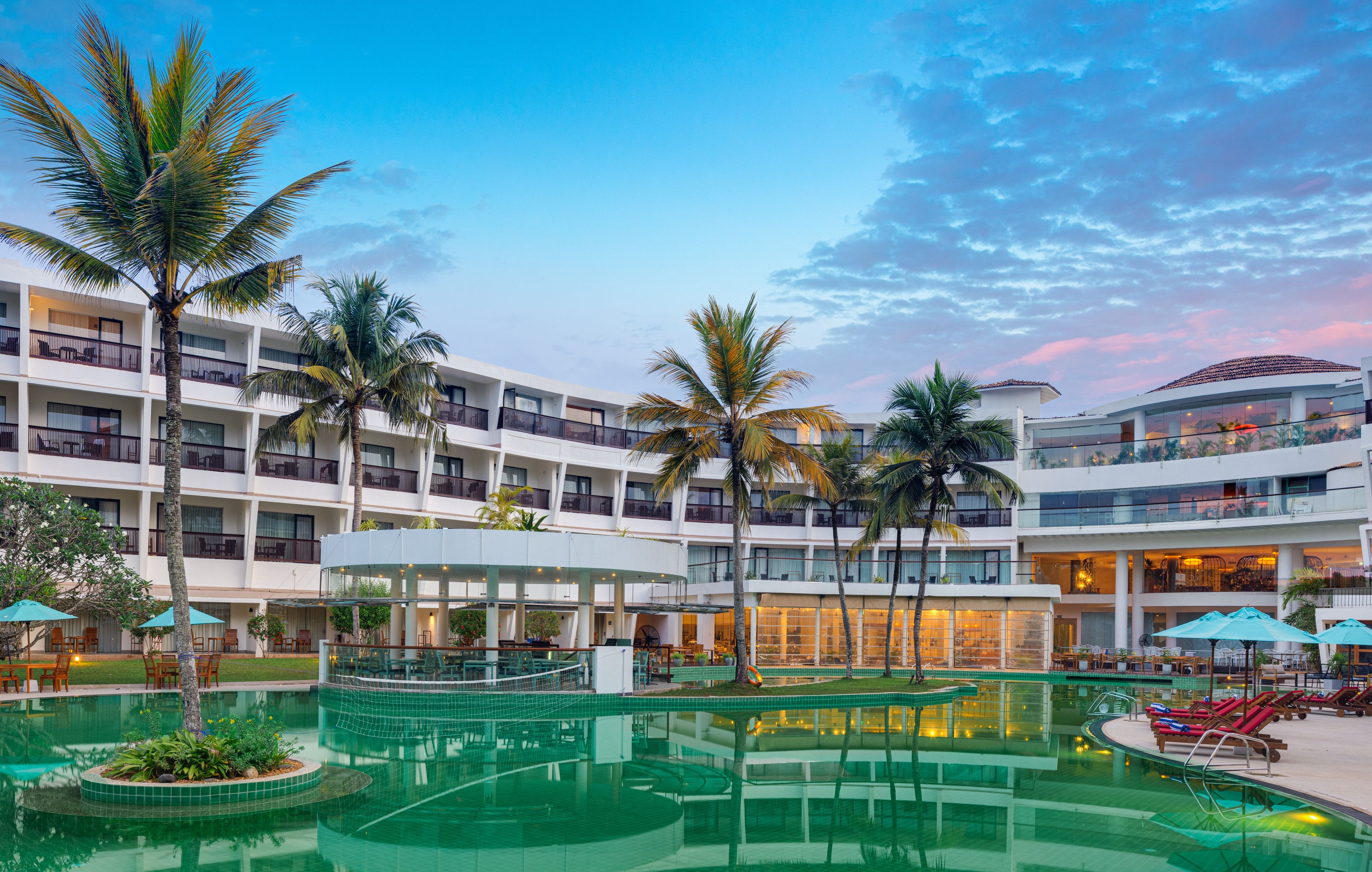 Un hotel con piscina, palmeras y un edificio de varios pisos.