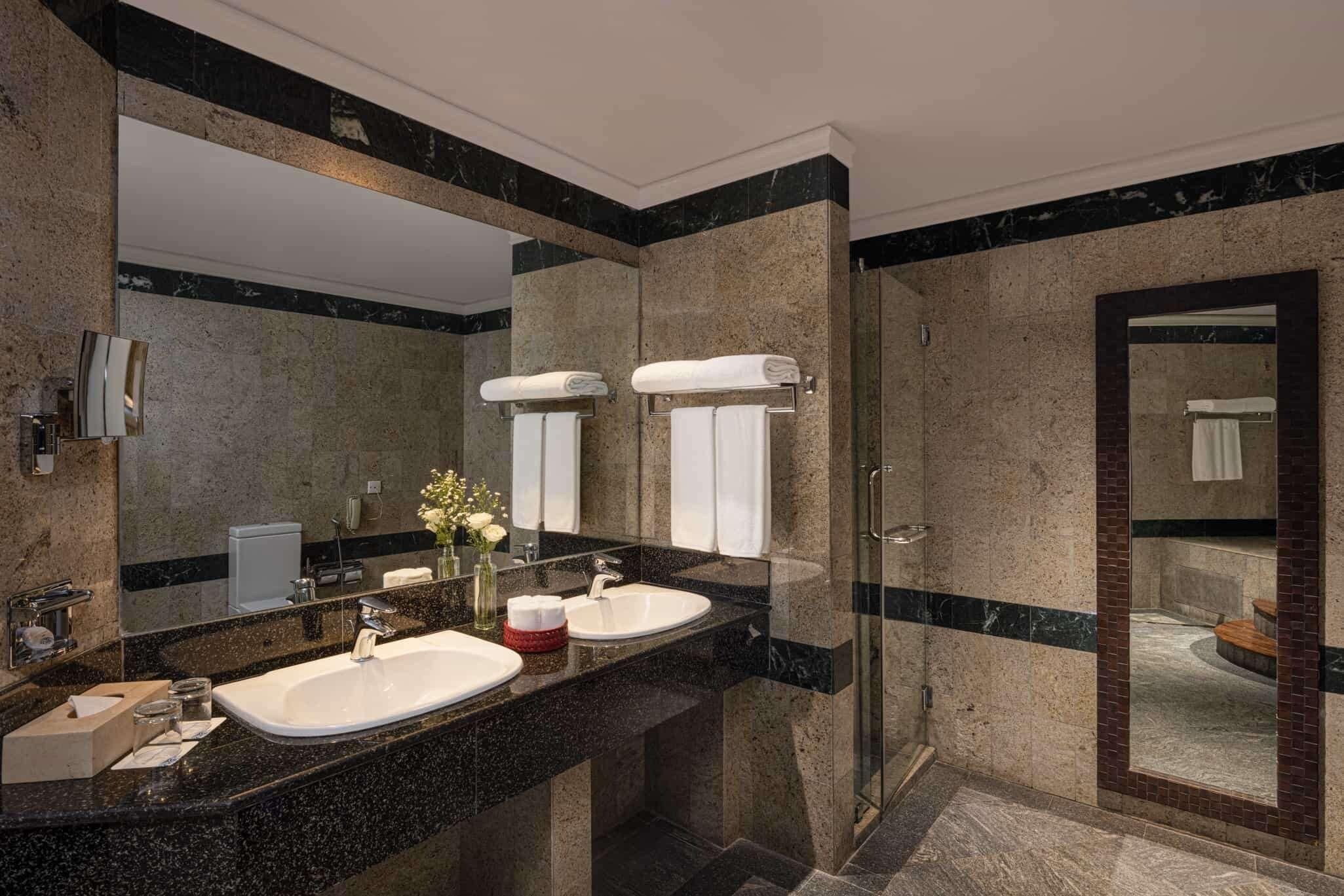 A modern bathroom with two sinks, a large mirror, and a glass shower enclosure.