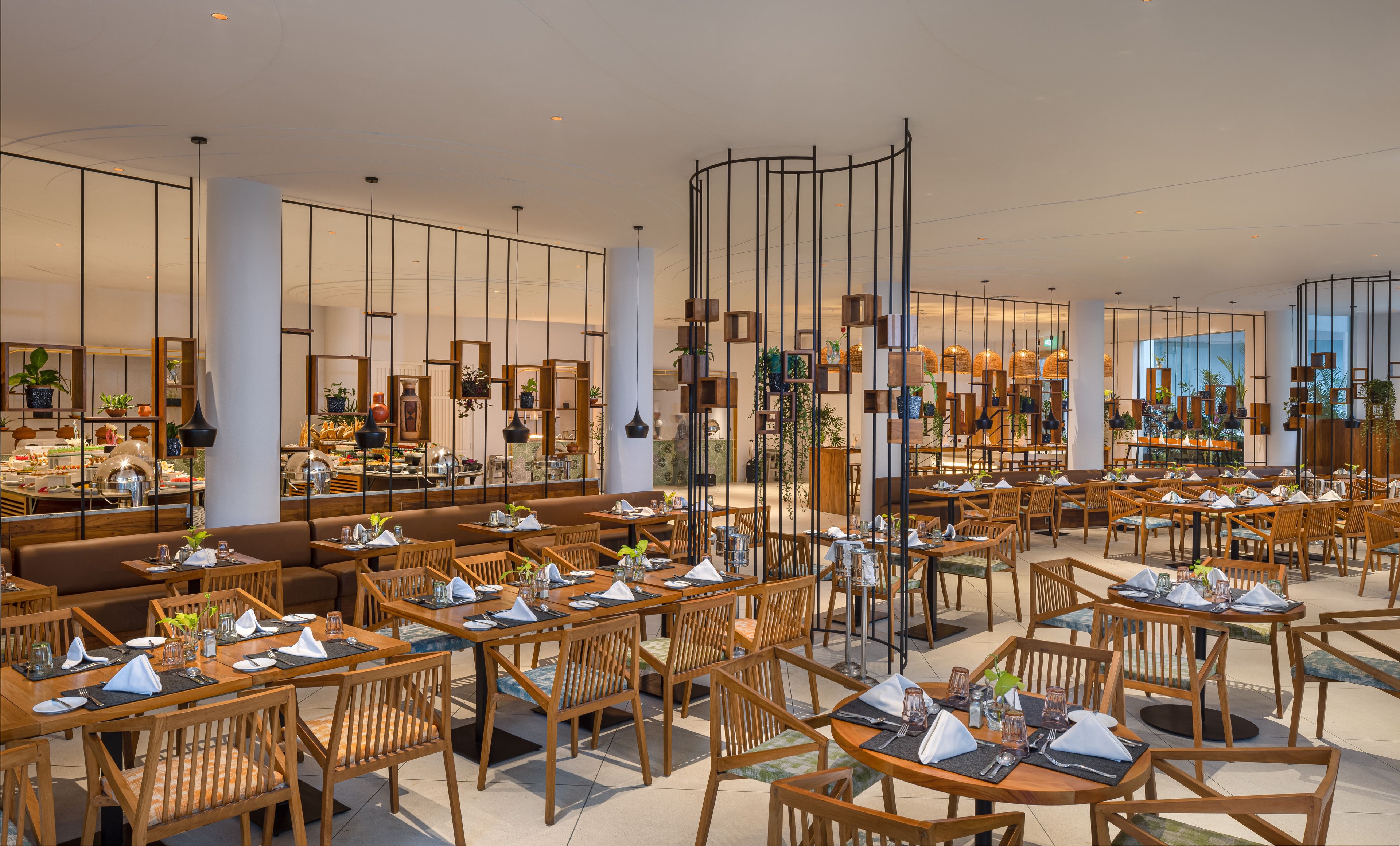 A spacious restaurant with multiple dining areas, wooden furniture, and a modern interior design.