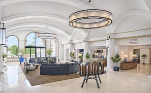 Un hall d’entrée spacieux, agrémenté d’un grand lustre, d’un espace salon et d’un comptoir d’accueil.