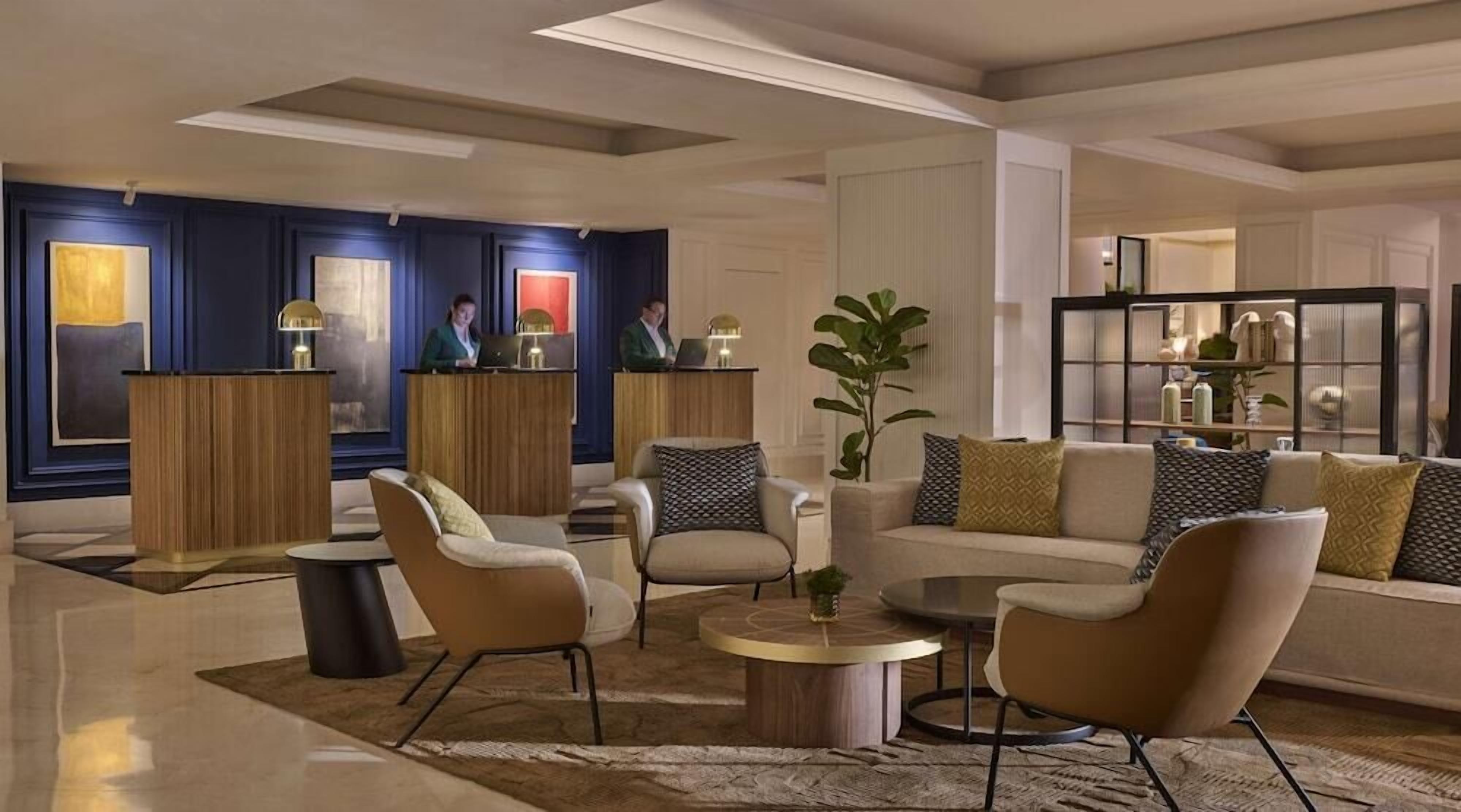 A modern lobby with a reception desk, seating area, and a bookshelf.