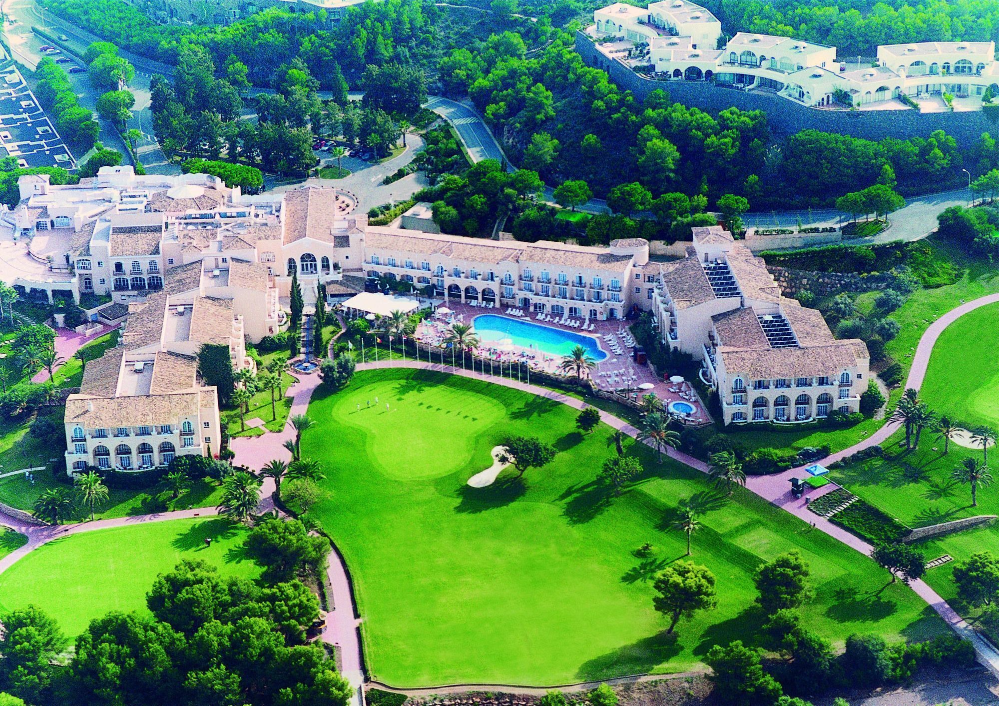 Un gran complejo turístico con varias edificaciones, una piscina central y jardines cuidados.