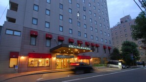 A hotel with a modern facade, multiple windows, and a prominent entrance with red awnings.