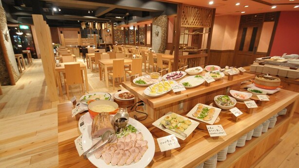 A buffet with various dishes, wooden tables, and chairs.