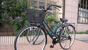 A bicycle parked on a tiled surface with a basket attached to the front.