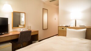 A hotel room with a bed, a desk with a chair, a television, a mirror, a bedside table with a lamp, and a phone.