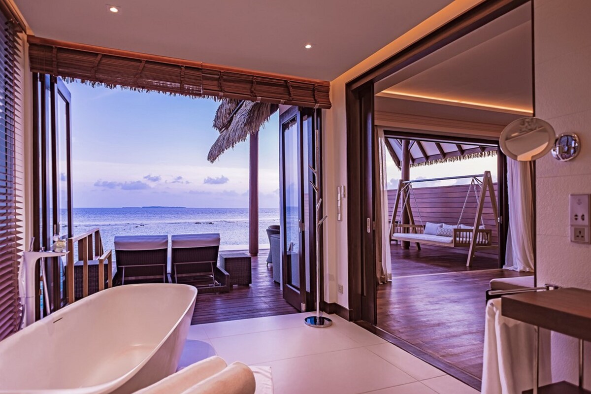 Ein modernes Badezimmer mit Badewanne, Duschbereich und Blick auf den Strand.