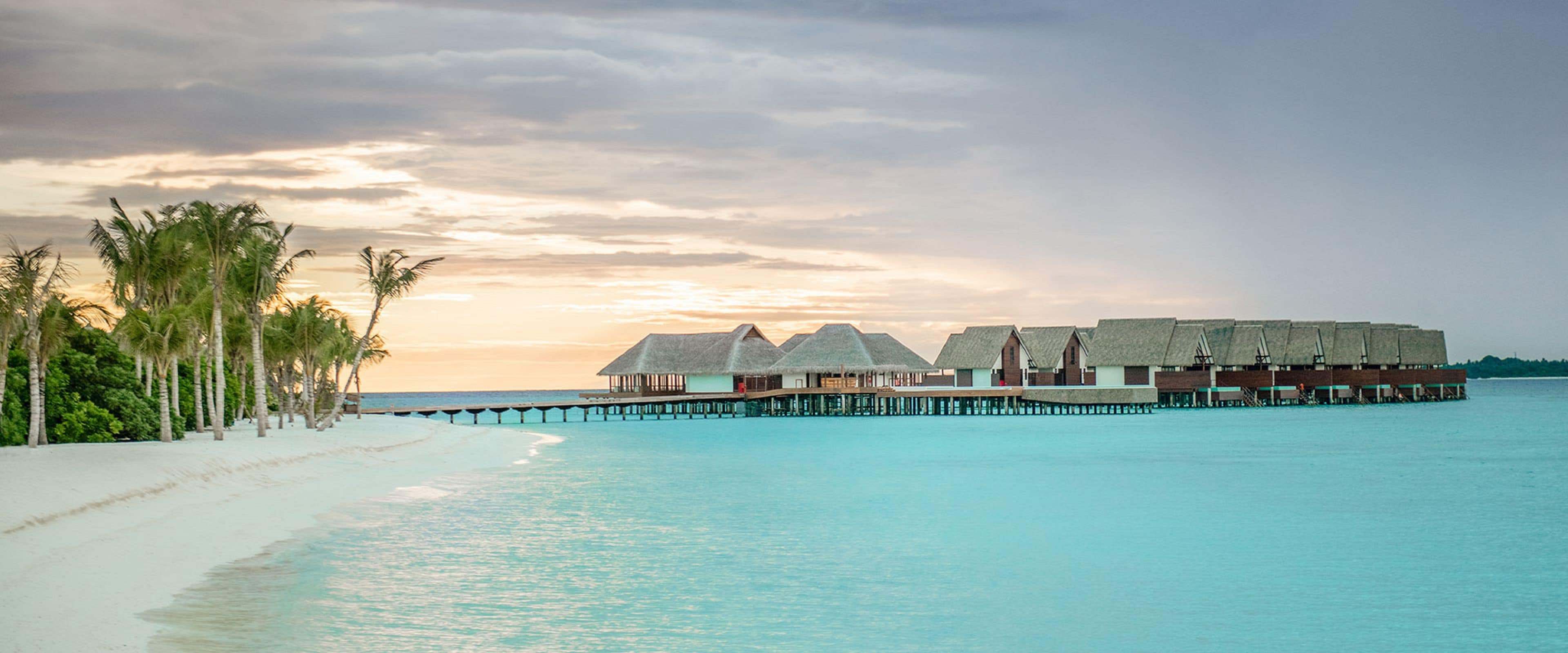 A beachside resort with overwater bungalows, a sandy beach, and a calm sea.