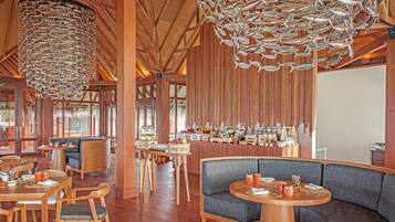 A spacious restaurant with wooden beams, a high ceiling, and a bar area with various food and drink displays.