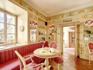 Une pièce dotée d’une table ronde, d’un banc recouvert d’un tissu rouge et de décorations murales élaborées.