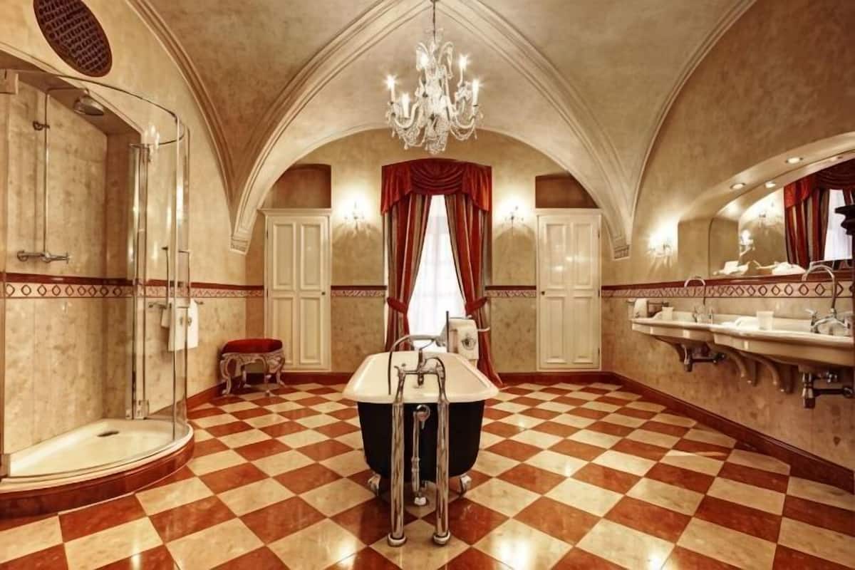 A spacious bathroom with a checkered floor, a large bathtub, a shower, and multiple sinks.
