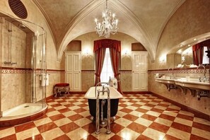 Un baño espacioso con piso a cuadros, una bañera grande, ducha y varios lavamanos.