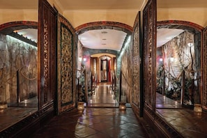 Un vaste hall d’entrée agrémenté de décorations raffinées, doté d’un mur en pierre et surmonté d’un lustre.