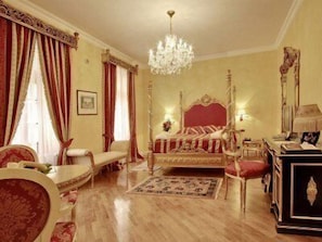 Ein Schlafzimmer mit einem großen Bett, einer Chandelier, einem Schreibtisch und einem Stuhl.