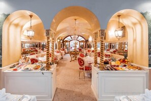 Une salle à manger d'hôtel avec de nombreuses tables, des nappes blanches et une arche centrale.