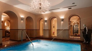 A swimming pool with a geometric tile border, surrounded by arched doorways and a chandelier. - Alchymist Grand Hotel and Spa (Prague)